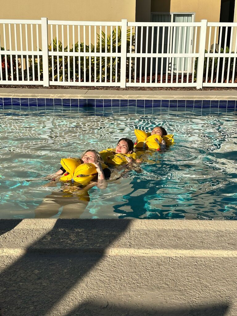 Students in life vests practicing a water survival drill in the pool