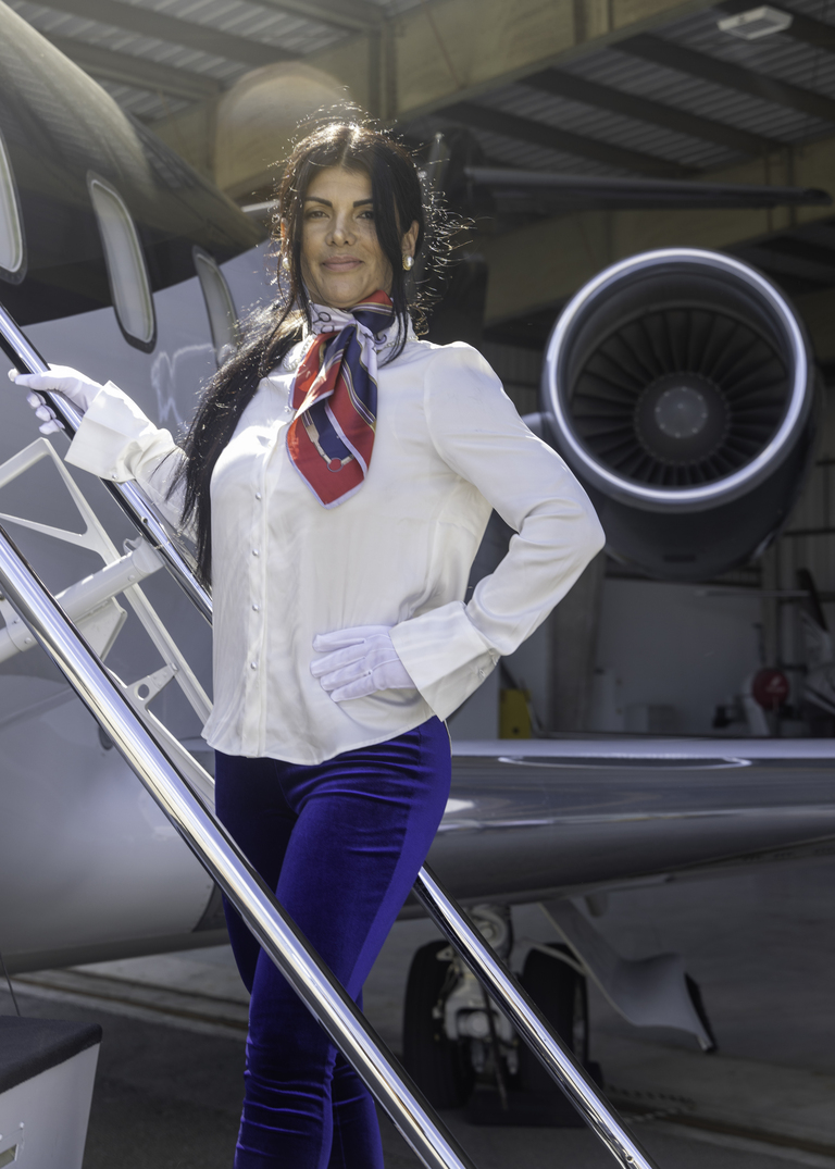 Graduate with a scarf and white gloves on the airstair of a business jet